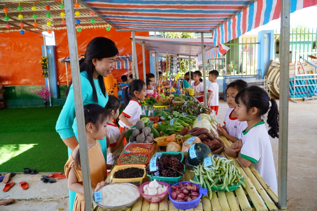 Cô và trò Trường Mầm non Ea Nam (xã Ea Nam) hào hứng tham gia phiên chợ quê tại sân trường. 