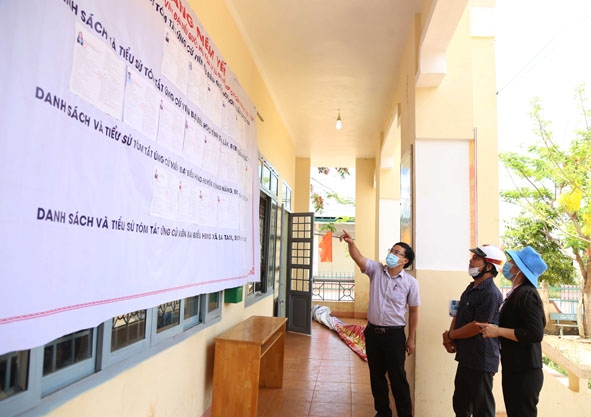 Cử tri xã Ea Tam theo dõi bảng niêm yết danh sách cử tri và tiểu sử tóm tắt của các ứng cử viên được niêm yết tại UBND xã. 