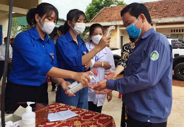 Các đoàn viên, thanh niên Huyện Đoàn Cư M'gar đo thân nhiệt, rửa tay sát khuẩn, phát khẩu trang, hướng dẫn người dân tham gia bầu cử. 