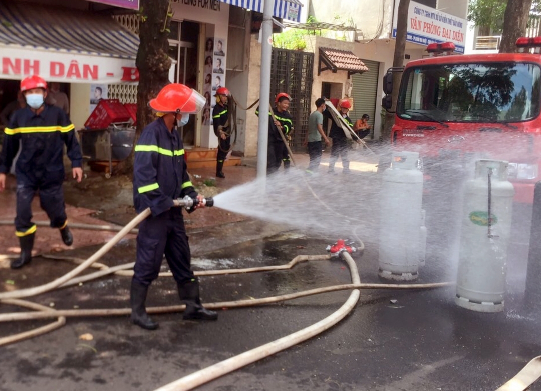 Lực lượng chữa cháy làm mát các bình gas của quán cơm Bé sau vụ cháy.  