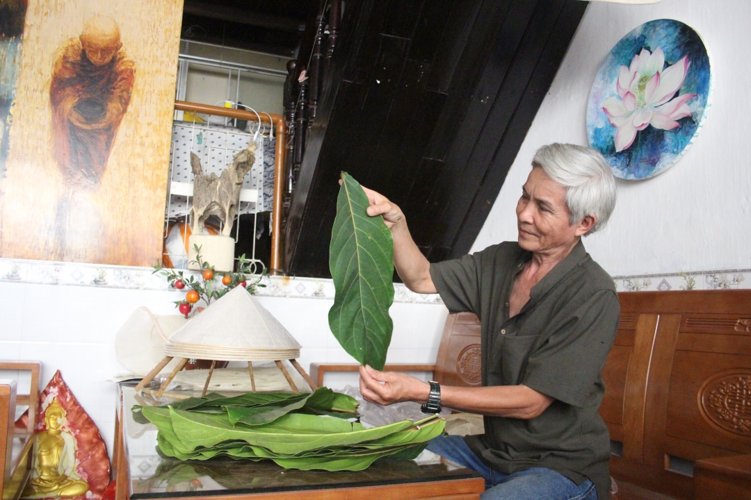 Nghệ nhân  Võ Ngọc Hùng  chuẩn bị nguyên liệu  lá bàng  làm nón. 