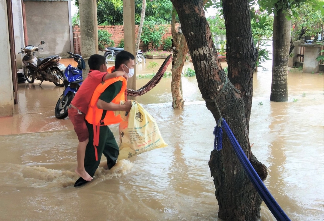 Chiến sĩ bộ đội đưa một trẻ em ra khỏi ngôi nhà bị mưa ngập vào năm 2020. Ảnh: N.Lân