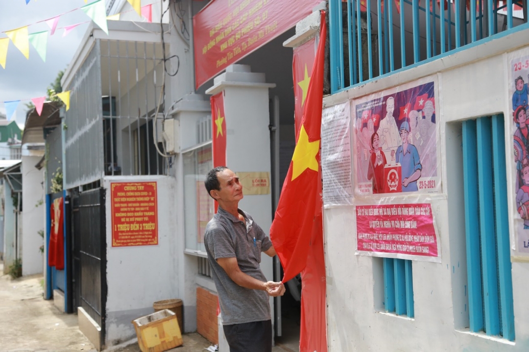 Ông Nguyễn Thanh, tổ trưởng TDP 7, phường Tân Tiến tự bỏ kinh phí để làm pano tuyên truyền và trang trí cờ hoa tại khu vực bầu cử của TDP.