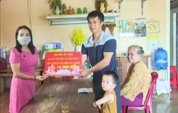 Đồng chí Đào Thị Thanh An, Phó Bí thư Thường trực Huyện ủy (bìa trái) trao tiền hỗ trợ cho gia đình em Nguyễn Hoàng Lâm, thôn Yên Thành 1, xã Đắk Nuê. 