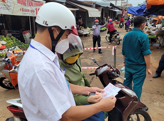 Kiểm tra thẻ vào chợ của một người dân trước khi vào chợ mua sắm hàng thiết yếu